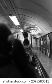 LONDON, UNITED KINGDOM - Nov 03, 2021: A Vertical Grayscale Shot Of People On The Subway Station Escalator In London, UK