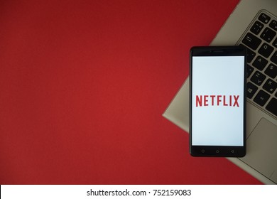 London, United Kingdom, October 23, 2017: Netflix logo on smartphone screen placed on laptop keyboard. Empty place to write information with red background.