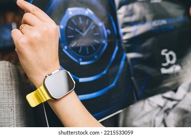 London, United Kingdom - Sept 28, 2022: Fashionable Woman Looking At Large Watch Advertising Inside Newsweek Wearing New Apple Watch Ultra By Apple Computers On Her Wrist