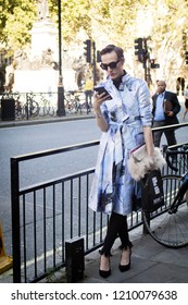 LONDON, United Kingdom- SEPTEMBER 14 2018: People On The Street During The London Fashion Week. Drag Queen In A Lilac Dress Robe Looks In The Phone