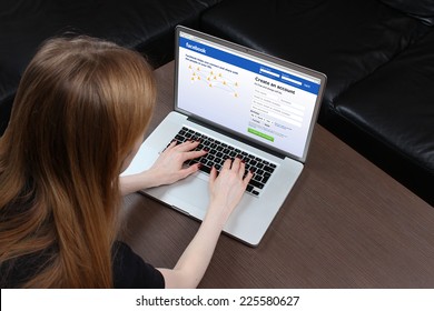 London, United Kingdom - September 24, 2014: Facebook Homepage On Computer Screen Teenage Girl Typing On Laptop Keyboard Logging Into Famous Social Network Facebook Home Page And Signing Up