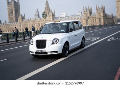 London, United Kingdon - 05.04.2022: White Electric Taxi On Westminster Bridge In London With Big Ben And Westminster Palace In The Background