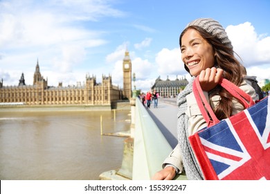 London Woman Holding Shopping Bag Near Big Ben. Happy Woman Shopper Smiling During Travel Vacation In London. Multicultural Asian Caucasian Female Traveler On Westminster Bridge.