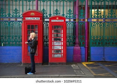 LONDON-ENGLAND, June 10, 2017:  Blond woman talking on mobile phone in front of 2 red phone booths model K-2 made in Smithfield market the largest wholesale meat market in the UK