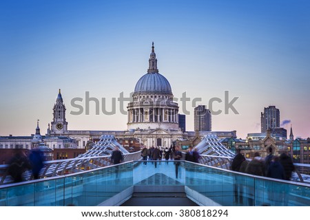 Londoners walking through Millennium Bridge with St.Paul's Cathedral at the background after sunset - London, UK