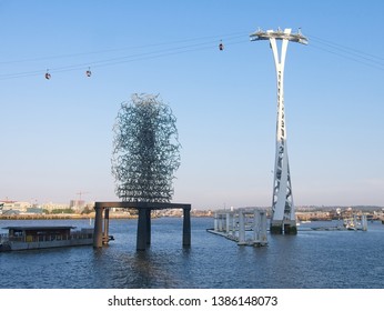 London,UK - 21 APR 2019: The Quantum Cloud, A Contemporary Sculpture By Anthony Gormley On A Plinth On The River Thames. The Emirates Air Line Cable Car Are Seen In The Blue Sky Background.