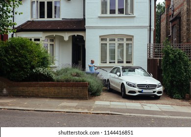 London/UK - July 21 2018: Man Washing His Car On The Terrace In Front Of His House In A Suburb Of London, UK