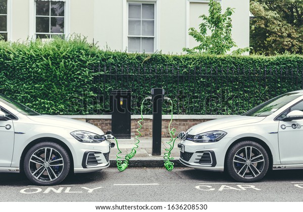 London/UK-30/07/18: two white Volkswagen\
Golf GTE cars charging at a charging point on a street in London.\
The Golf GTE is a plug-in hybrid version of the Golf\
hatchback