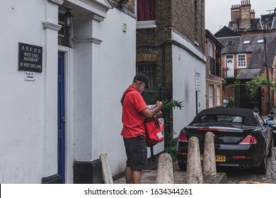 London/UK-30/7/18: Royal Mail's Postman Delivering Mail. A Mail Satchel Is A Type Of Mailbag That A Letter Carrier Uses Over-the-shoulder For Assisting The Delivery Of Mail On A Designated Route