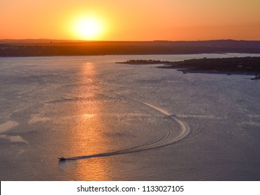 A Lone Boat Enjoys The Breathtaking Sunset Views On Lake Travis In The Texas Hill Country Near Austin, Texas.