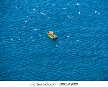 A Lone Boat With Industrial Fishermen In The Open Sea With A Rod And Nets. The Concept Of Poaching And Illegal Fishing.