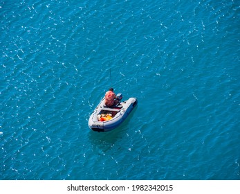 A Lone Boat With Industrial Fishermen In The Open Sea With A Rod And Nets. The Concept Of Poaching And Illegal Fishing.