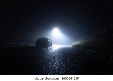 A Lone Car, Parked On The Side Of The Road, Underneath A Street Light, On A Spooky, Scary, Rural, Country Road. On A Foggy Winters Night