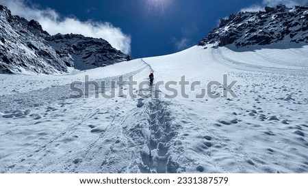 A lone climber climbs the Delaunay Pass, rear view. Climbing Mount Belukha. View of a snow-covered trail in the Altai mountains. Beautiful snowy mountain winter landscape.