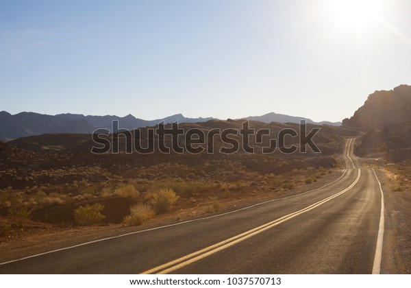 Lone desert road in a\
barren landscape