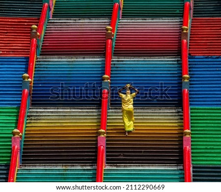 A lone devotee carrying milk up the stairs on a hindu temple in Malaysia