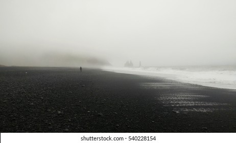 Lone distant figure walking through the fog on the black beach - Vik, Iceland - Powered by Shutterstock