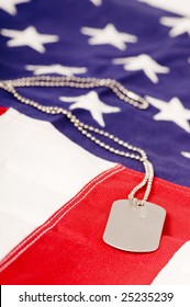 A Lone Dog Tag Sits On Top Of An American Flag