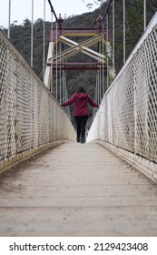 Lone Female Figure Walking Over A Bridge At Cataract Gorge In Tasmania