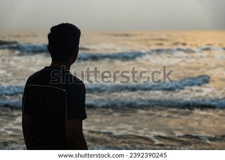 A lone figure stands mesmerized by the hypnotic sway of the ocean
