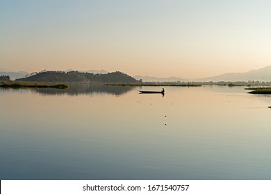 A Lone Fisher Man Rows His Boat On The Loktak Lake, Manipur At Dusk