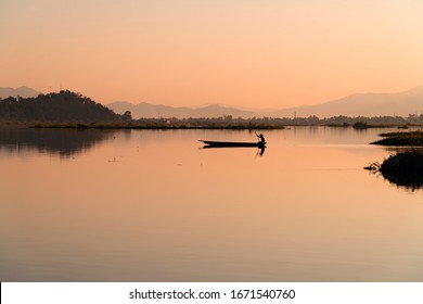 A Lone Fisher Man Rows His Boat On The Loktak Lake, Manipur At Dusk