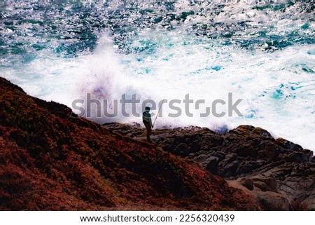 Lone fisherman on a rock with big waves crashing near him