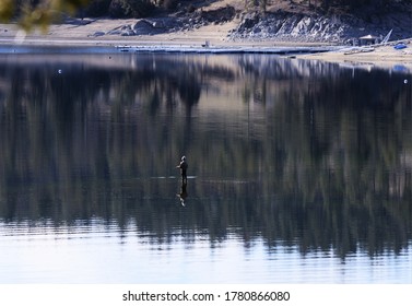 A lone fisherman is reflected in a shallow section of the Missouri River in Western Montana.