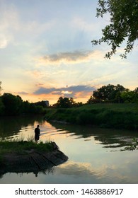 A Lone Fisherman Standing On The Bank Fishing At Sunset On Buffalo Bayou