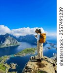 A lone hiker stands atop a rugged cliff, immersed in breathtaking vistas of Norway Lofoten Islands under a clear blue sky. Asian women visit the Lofoten