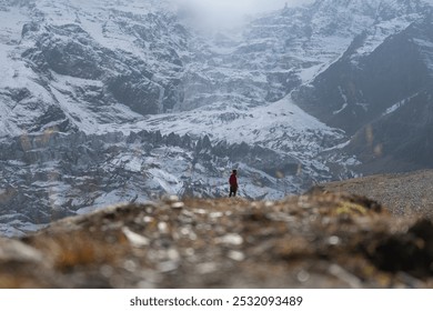 A lone hiker traversing a rugged snowy mountain landscape - Powered by Shutterstock