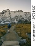 Lone Hiker Walking At Hooker Valley Track, Mount Cook National Park With Mount Sefton In The Background On An Overcast Day