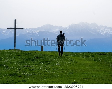 Lone Hiker Walking Toward a Mountain Cross under a Hazy Alpine Sky