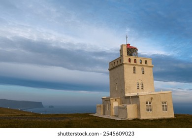 Lone lighthouse on a coastal cliff with a dramatic sunset sky and expansive ocean view. - Powered by Shutterstock