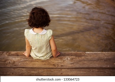 Lone little girl sitting on pier