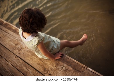 Lone little girl sitting on pier