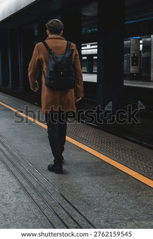 lone man with a backpack on the train station platform