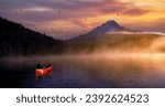 Lone man in a red canoe on Trillium Lake with Mt Hood looming in the background.  Steam and fog are rising from the lake.
