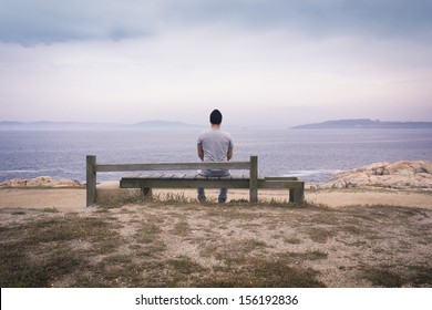 Lone man sitting in front of sea.