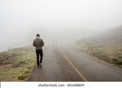 Lone man walking along the road through white fog - Powered by Shutterstock