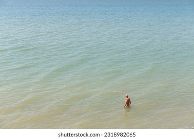 Lone mature man, topless. wading in the sea on a warm summer day seen from above - Powered by Shutterstock