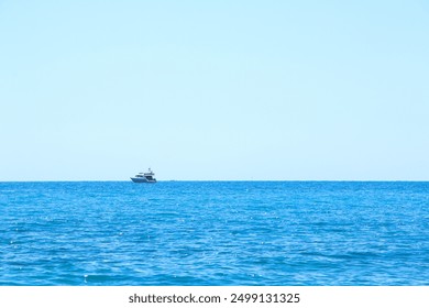 A lone motorboat sails on the vast blue ocean under a clear sky, creating a minimalist and serene maritime scene that highlights the beauty of open water and tranquility. Vacations on French Riviera. - Powered by Shutterstock