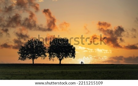Lone motorcyclist on country road in sunset