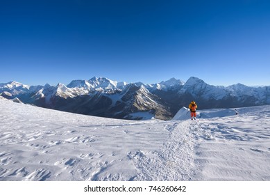 A lone Mountaineer walking down from Mera Peak in front of world's highest mountains: Mt. Everest, Lhotse, Makalu, Ama Dablam etc. A sunny day in the mountains. 