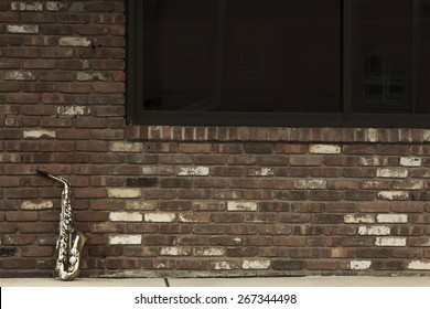 Lone old saxophone leans against brick wall outside abandoned jazz club - Powered by Shutterstock