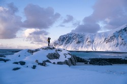 Lone Person Looks Onwards At A Mountain In Snow During Sunset With The Peak Visible. Scenic Landscape Photo Composite. The Stony Beach And Cliff Of Rocky Bay. Blue Tones Of February Sunset, 