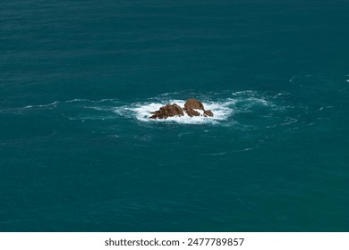 Lone rock formation surrounded by vast expanse of ocean. Waves gently crashing against rocks create isolated scene, emphasizing natural beauty and tranquility of marine environment. - Powered by Shutterstock