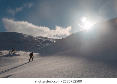 A lone skier ascends a pristine snow-covered slope under a vibrant blue sky. A breathtaking view of a snow-covered mountain range - Powered by Shutterstock