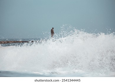 A lone soldier stands on a stormy pier, gazing into the misty distance, with waves crashing around him, capturing a moment of introspection and resilience. - Powered by Shutterstock