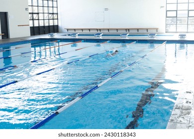 A lone swimmer practices in an indoor pool, with copy space. The setting suggests a focus on fitness or training, in a school or community center. - Powered by Shutterstock